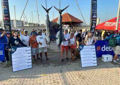 a group photo next to two fish caught that won La Patrona a fishing tournament